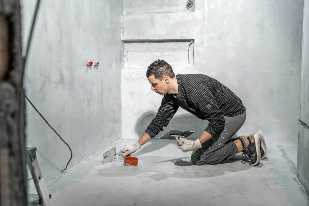 Man applying sealer on bathroom floor for renovation